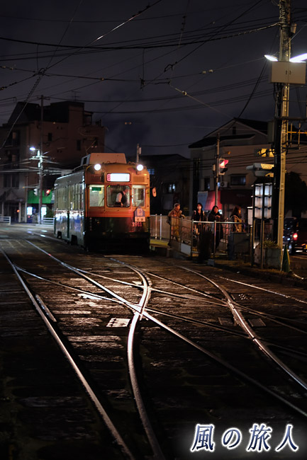 輝く線路と敷石　夕闇迫る冬の江波電停の写真